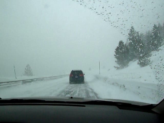 Cars moving through low-visibility snowfall requiring a winter storm driving kit